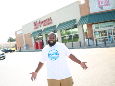 Man smiling in Greater Than HIV t-shirt in front of Walgreens