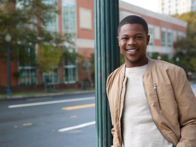 Man leaning against pole smiling